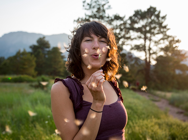 Person outside blowing a dandelion