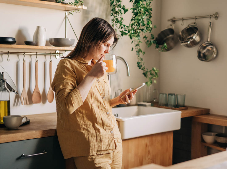 Woman in kitchen looking at her phone