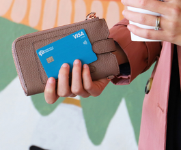 women holding coffee, purse and a visa card