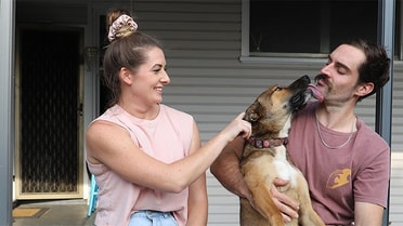 Couple out the front of new home with dog
