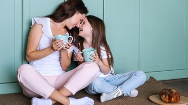 A mum and her daughter holding mint cups tapping noses