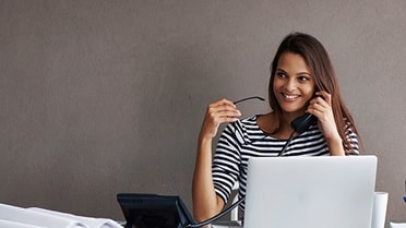 A woman with her laptop open - smiling on the phon