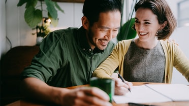 A woman smiling at a man smiling at him while signing a document