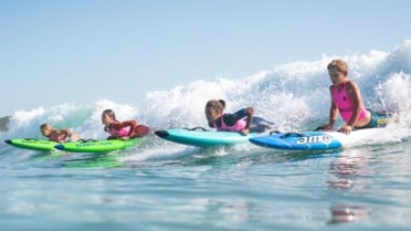 2024 Newcastle Permanent Nippers Season. three children surfing the waves.
