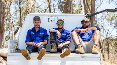 3 guys sitting on the back of the ute trunk smiling