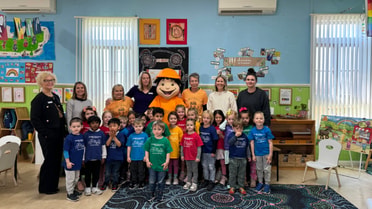 Employees children and mascot gathered smiling for a group photo