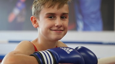 Kid wears boxing gloves smiling