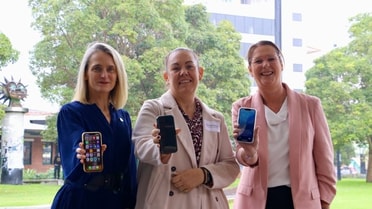 NPCF and Hunter DFV Consortium employees smile and hold phones to camera