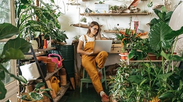 Woman in greenhouse on laptop