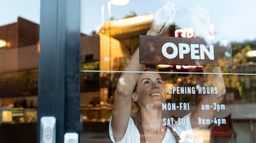 Person putting up open sign on cafe door