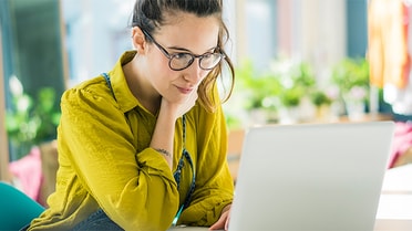 Woman in glasses stares intently at laptop