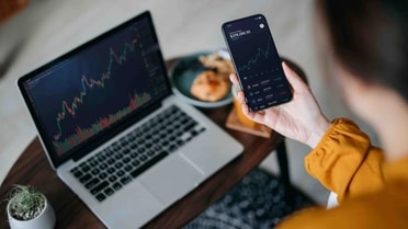 Phone held in hand next to laptop