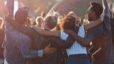 four friends intertwining shoulders in outdoor festival 