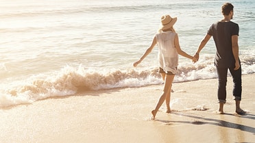 Woman and man holding hands by the beach 