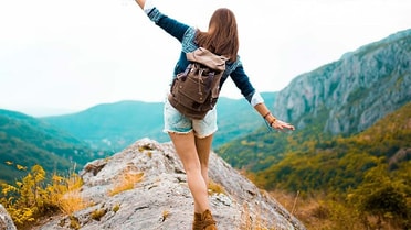 Woman tries to balance on rocks in nature 
