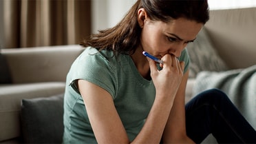woman looking down with a pen in her hand - concerned