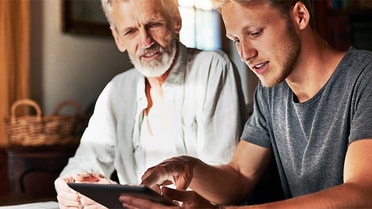 Man shows his dad information on his tablet, pointing