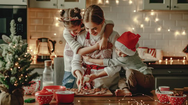 Mum decorates her baking with her daughter and son hugging her 