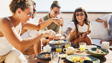 5 friends enjoy passing each other food for lunch outdoors 