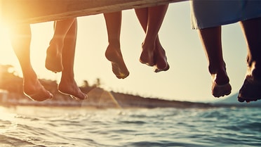 feet dangling from friends sitting on a wharf 