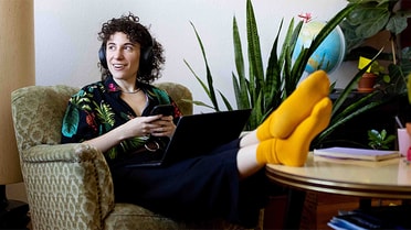 Woman with feet up on couch on phone and laptop