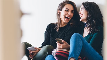 two women sitting down smiling at each other 