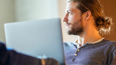 Man with his laptop open looking sideways 