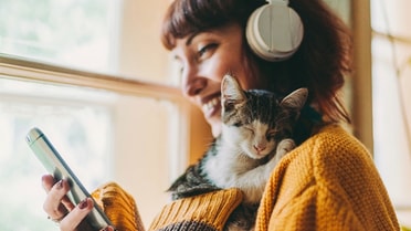 Woman holding kitten while typing on phone