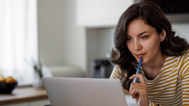 Woman holding her pen thinking looking at her laptop 
