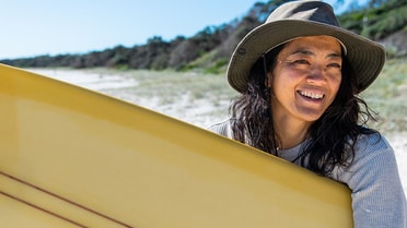 Woman holding a surfboard smiling