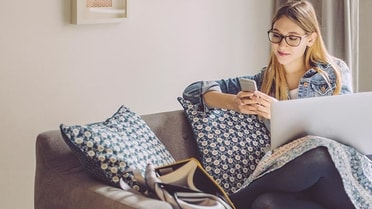 Woman sitting in couch on her phone 