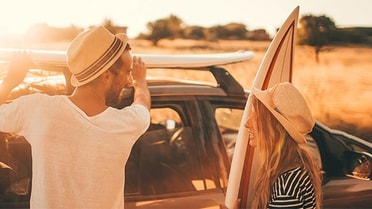 Couple putting surfboards onto car