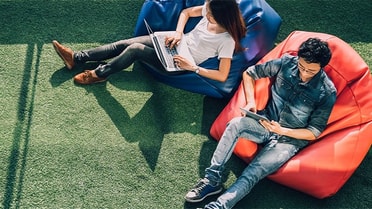 students sitting on bean bags on laptop