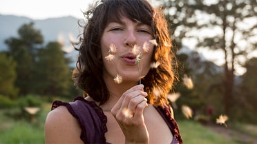 Woman blowing on a dandelion