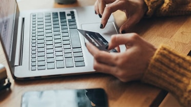 person holding their card while using their laptop