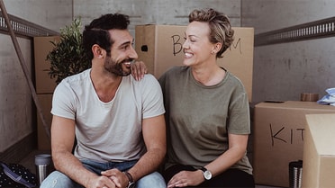 Couple sitting in the back of a moving truck with all of their boxes