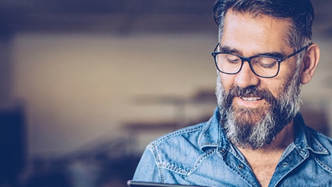 Man smiling down on his tablet with a shed background