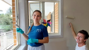 Volunteers painting home wall