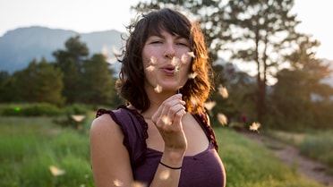 A woman blowing on dandelions