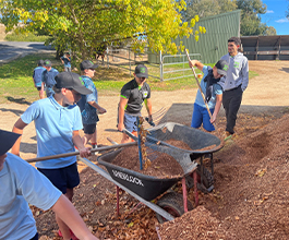 Boys shoveling dirt into wheelbarrow