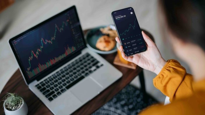 Phone held in hand next to laptop