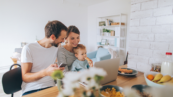 Young family at Kitchen counter using their devices