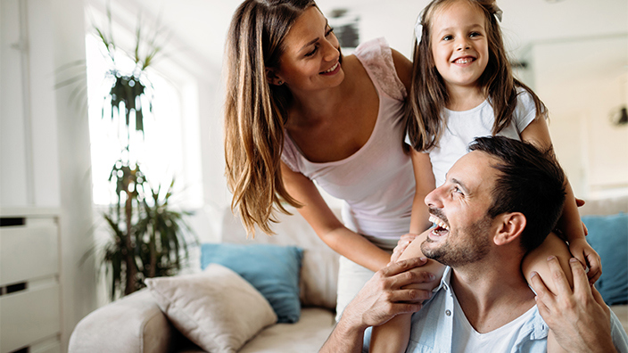 Young family in lounge room smiling